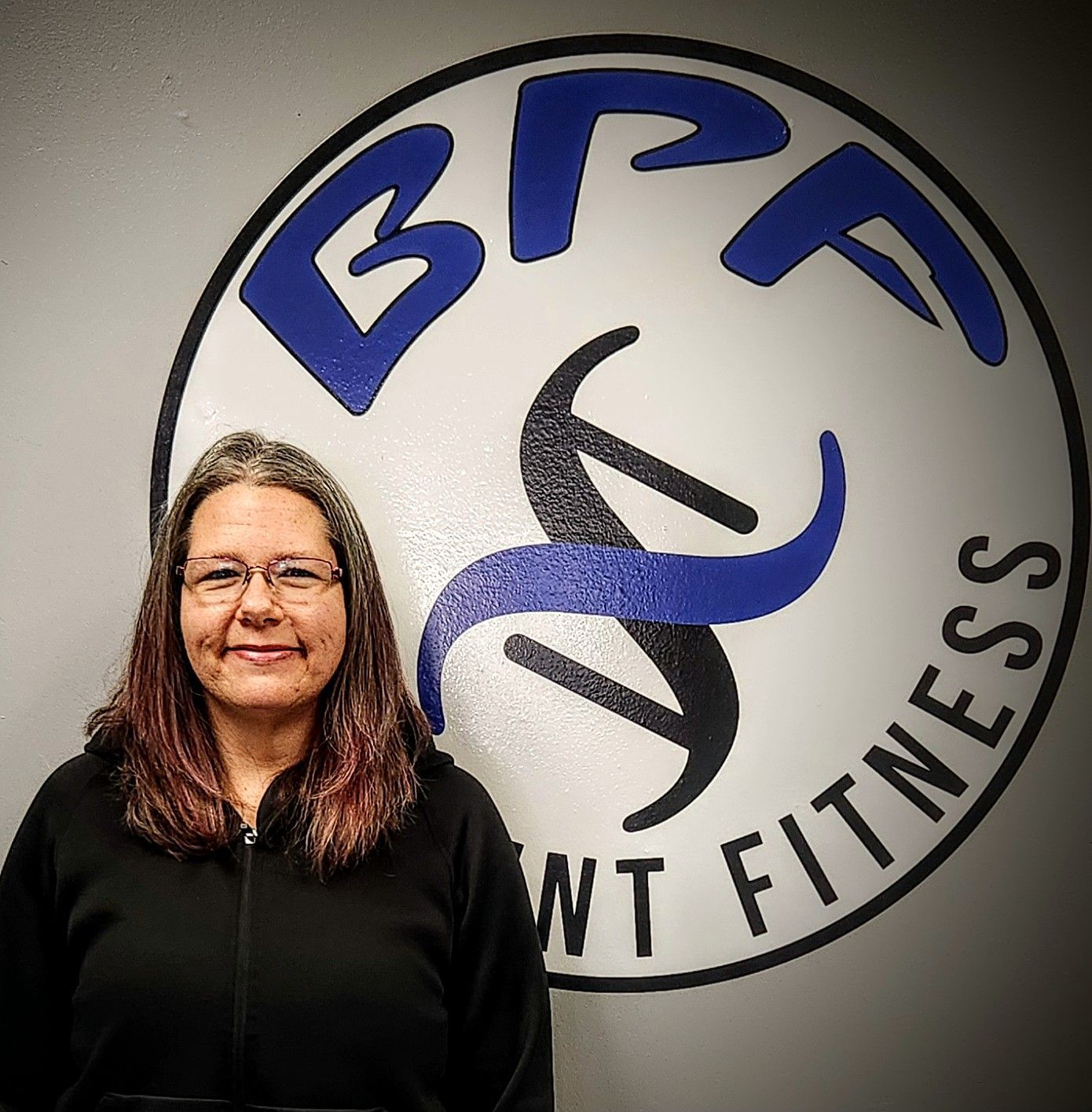 A woman is standing in front of a bfp wt fitness logo