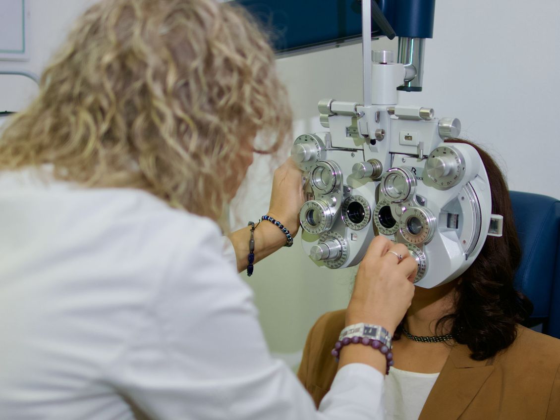 Esame della vista con forottero; l'optometrista regola le lenti di un paziente in una clinica.