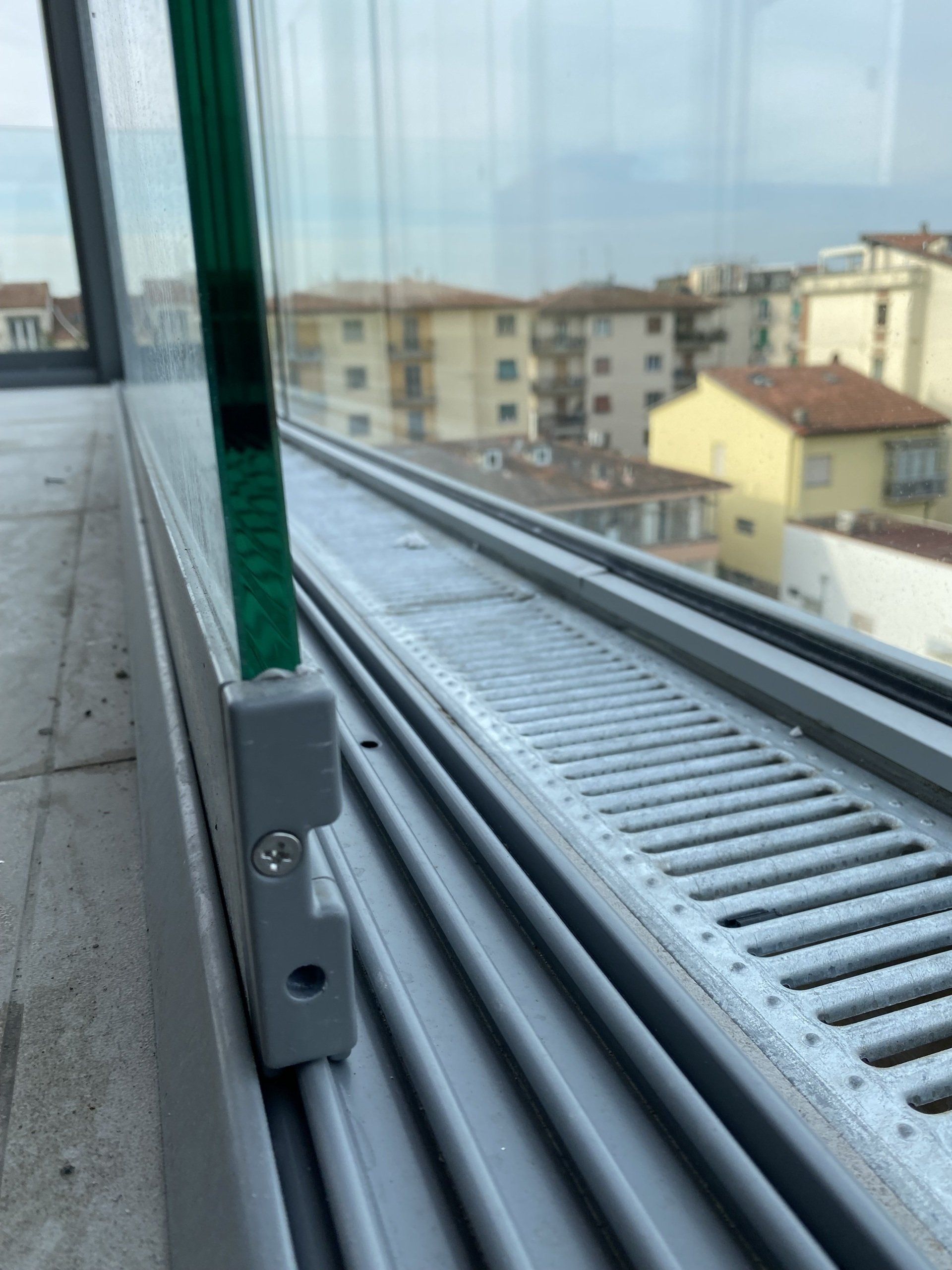 Primo piano del pannello di vetro e del telaio grigio della finestra con vista sulla città sullo sfondo.