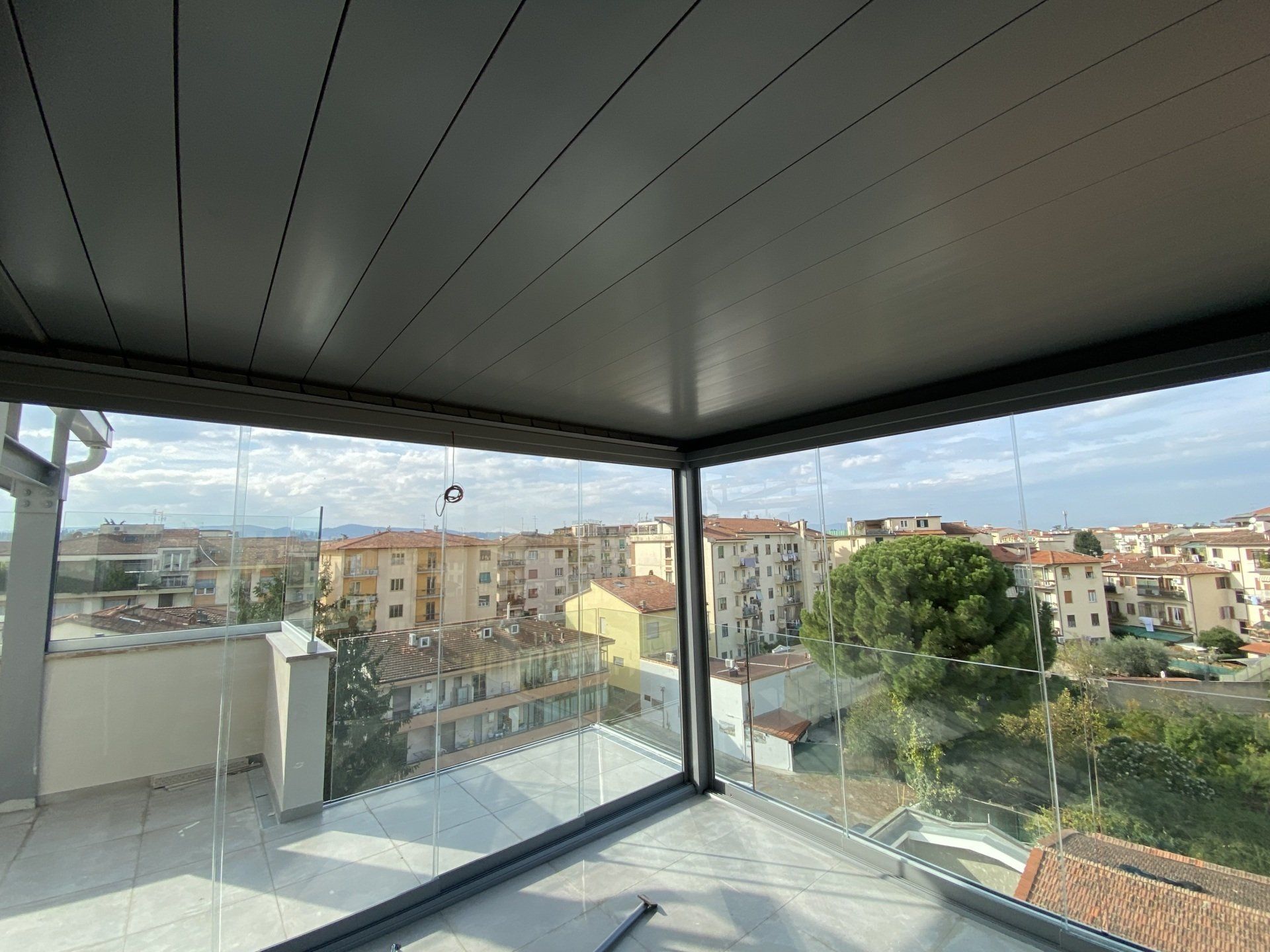 Recinto con pareti in vetro sul tetto con vista sugli edifici e sul cielo.