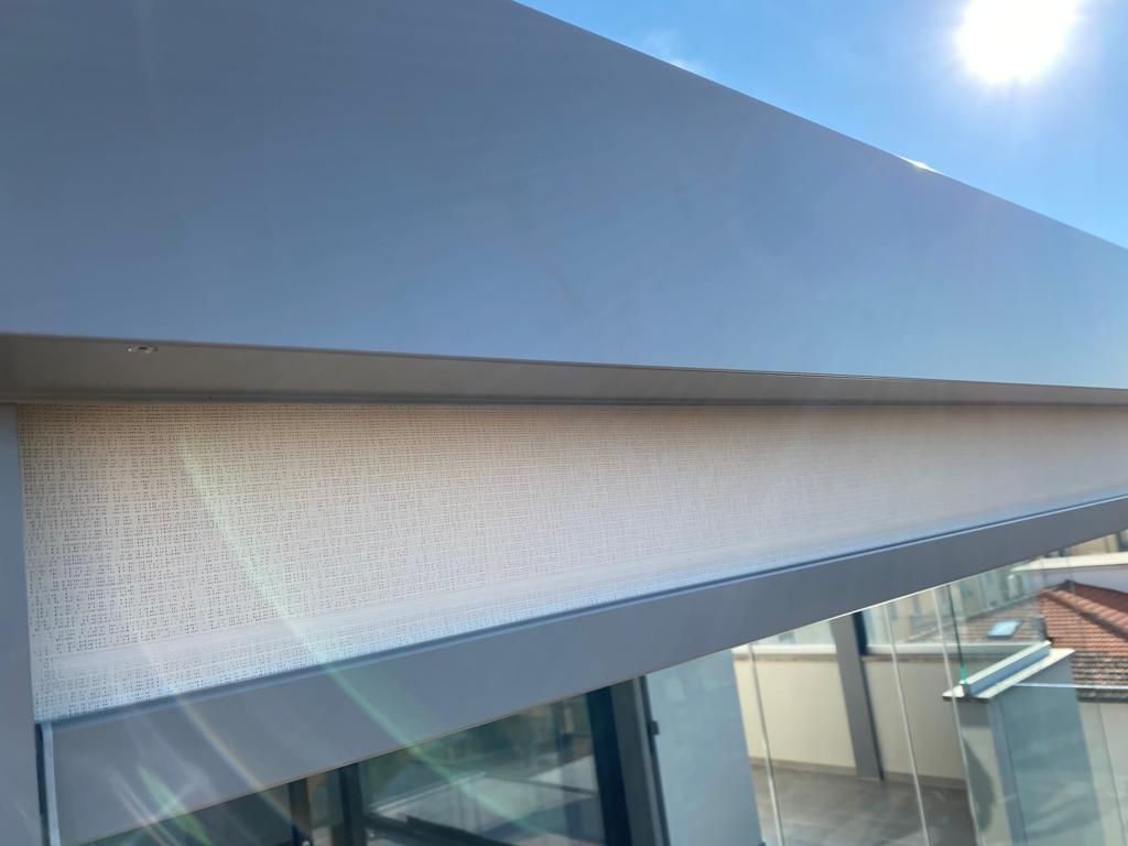 Tenda da sole grigia con tenda a rullo beige, in una giornata di sole.