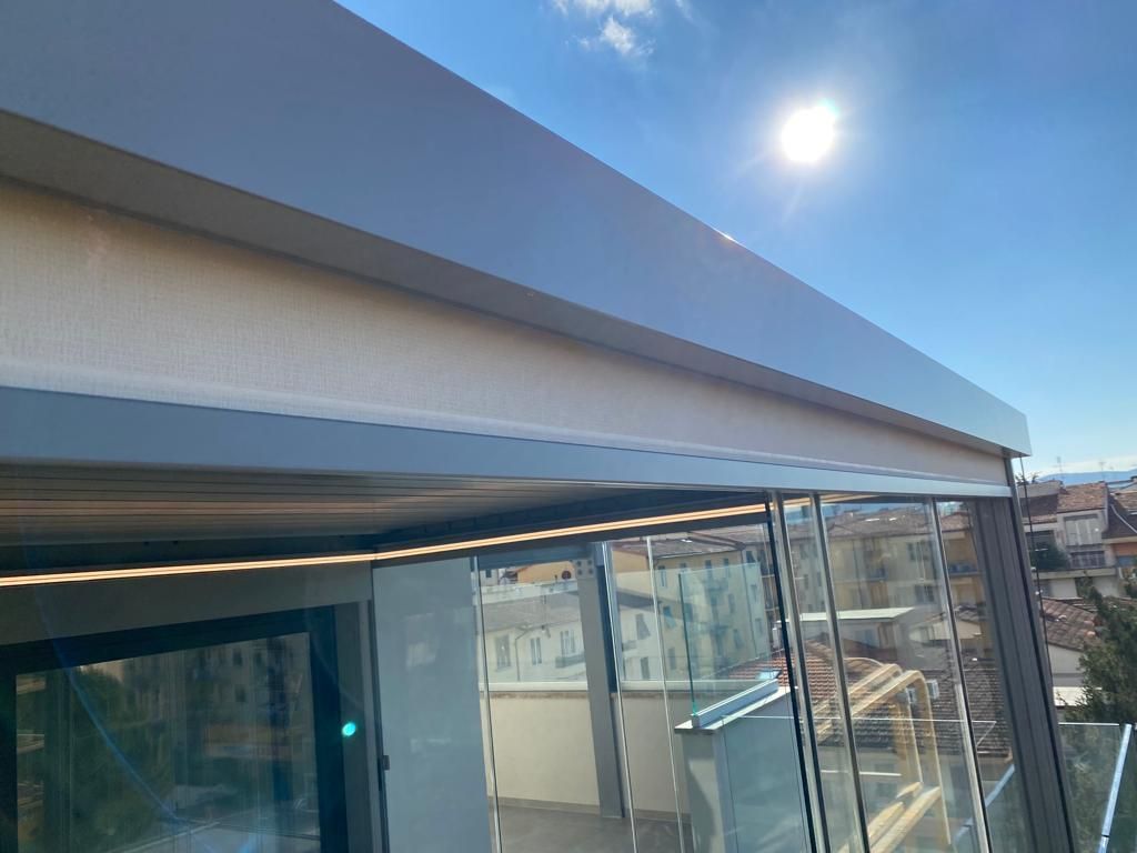 Esterno di un edificio moderno con pareti in vetro e una struttura sopraelevata illuminata dal sole.