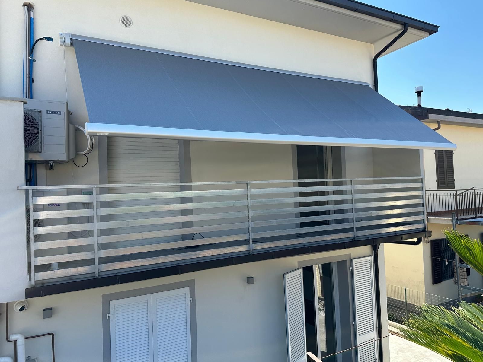 Tenda da sole grigia sopra un balcone con ringhiera in metallo.