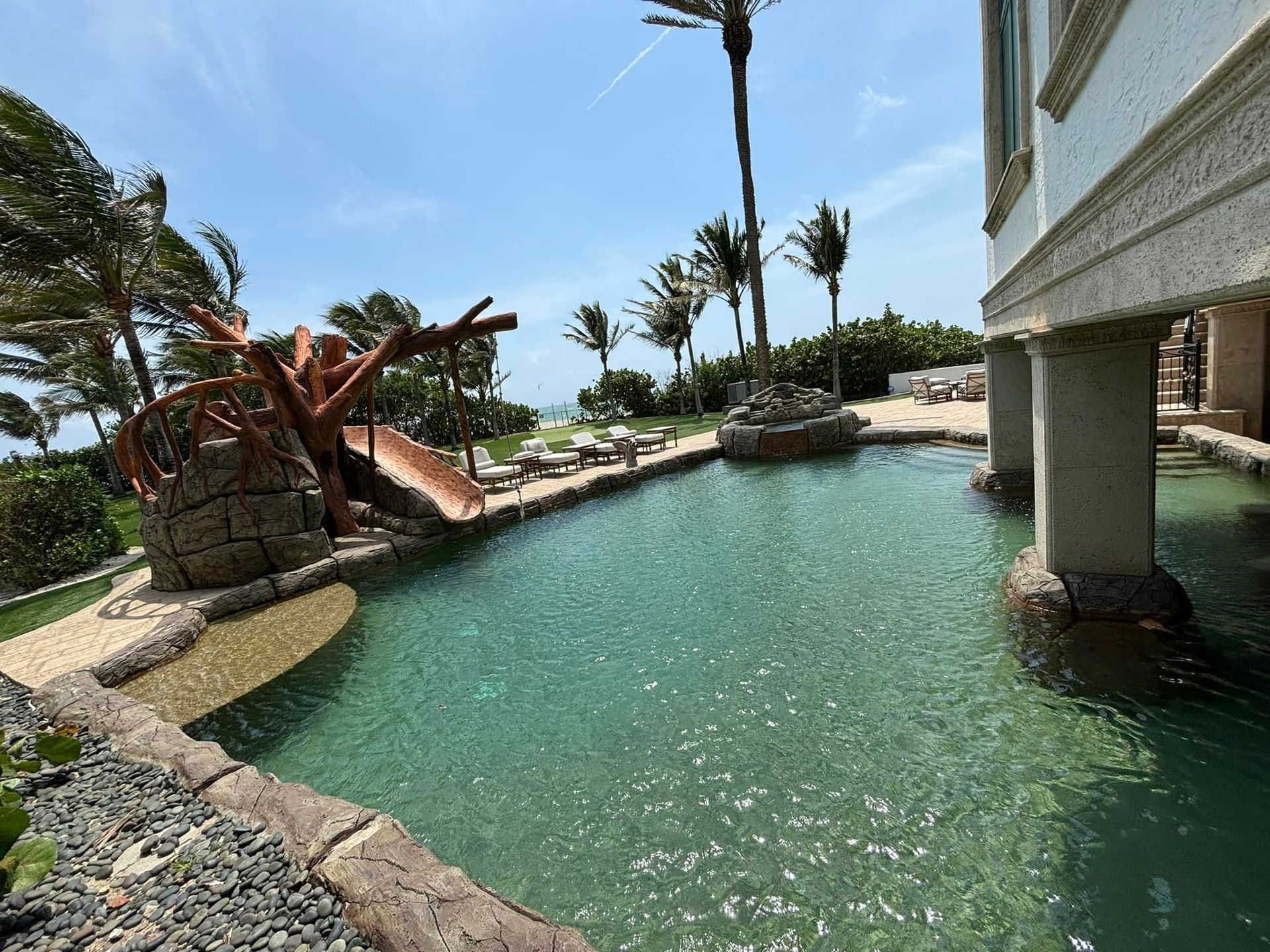 A large swimming pool is surrounded by a white fence.