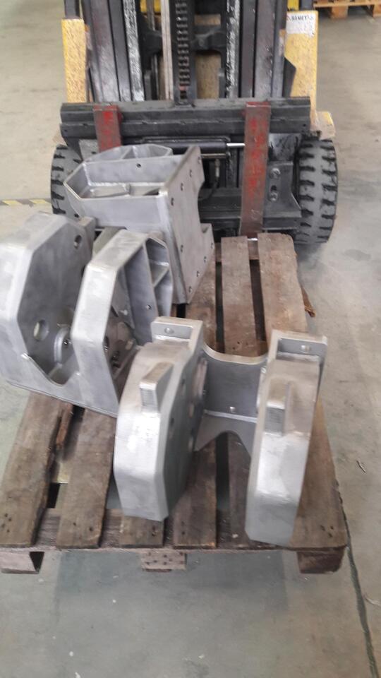 Pallet da magazzino con grandi accessori per carrello elevatore in metallo grigio su listelli di legno