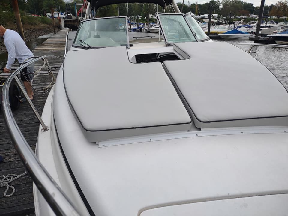 White boat cockpit with closed canvas covers docked at a marina, viewed from the bow