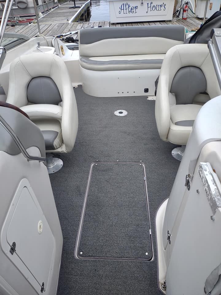 Boat cockpit with gray and white seating around a central carpeted walkway and storage hatch