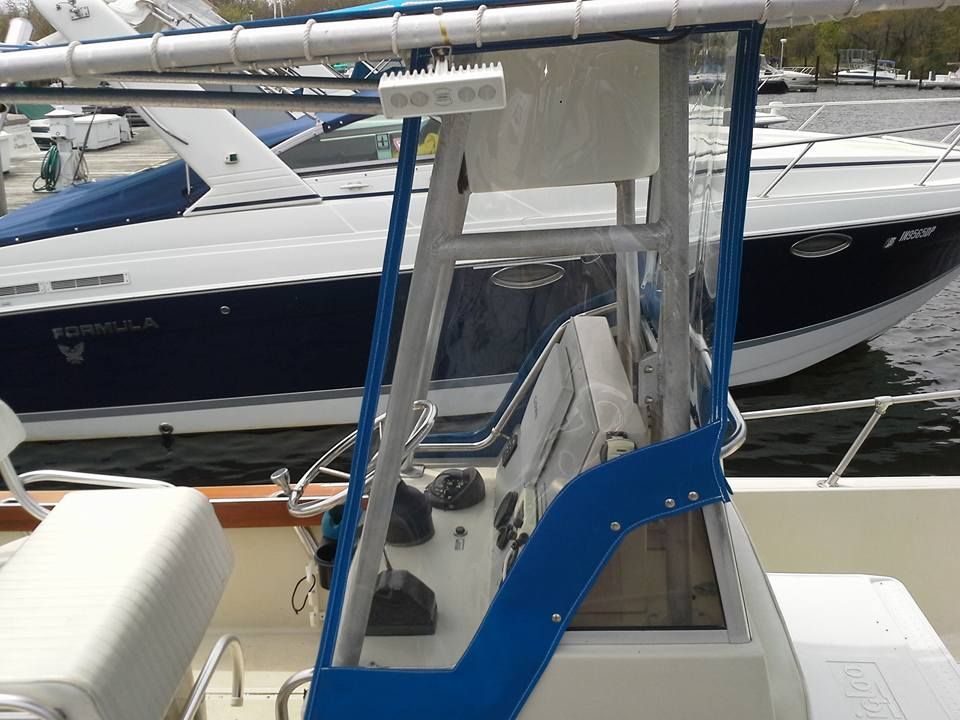 Blue-and-white boat cabin with clear windows docked beside a larger yacht in a marina