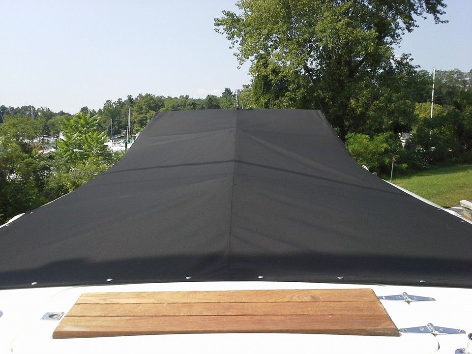 Black roof tarp covering a structure, seen from above with trees in the background
