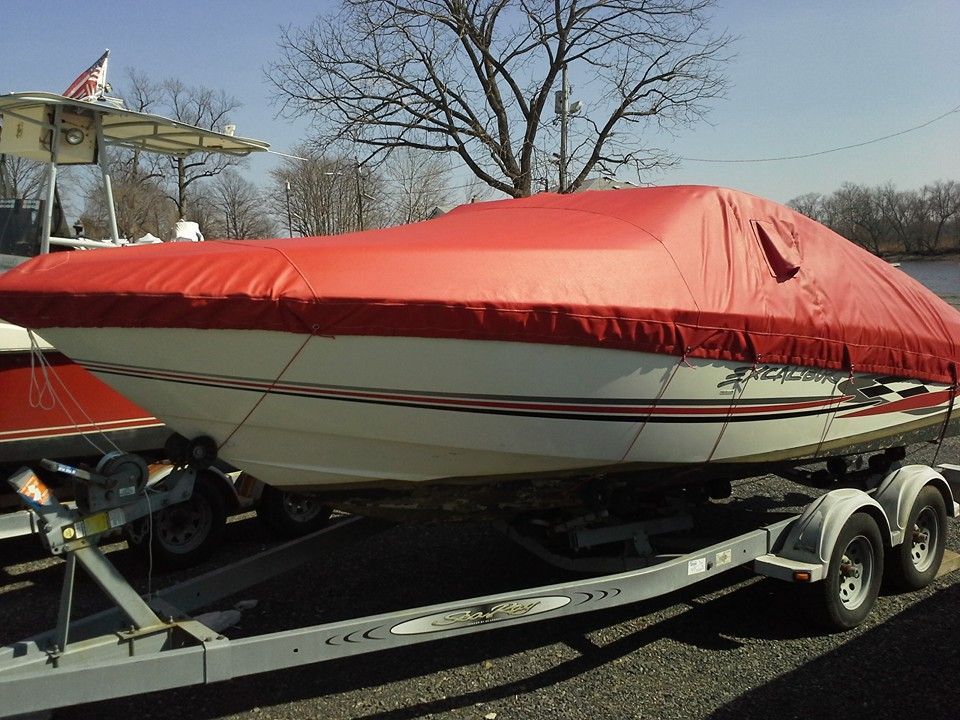 Red covered speedboat on a trailer parked outdoors in a lot