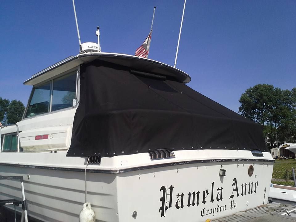 White boat with black canopy docked under a clear blue sky, named “Pamela Ann”
