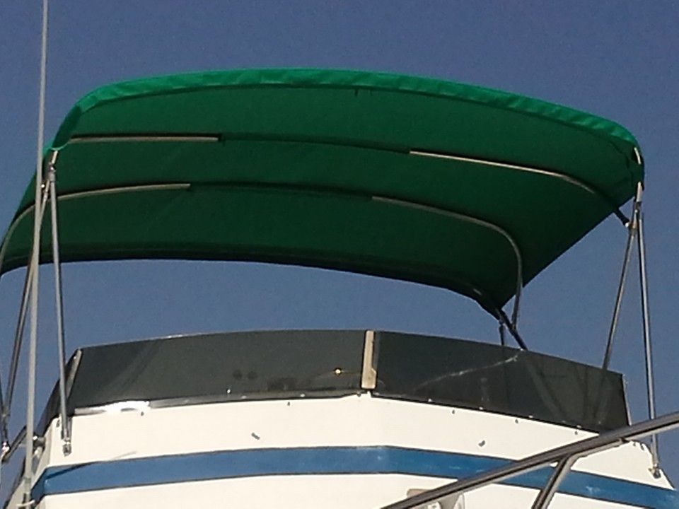 Small boat with a green canopy and white-and-blue hull against the sky.