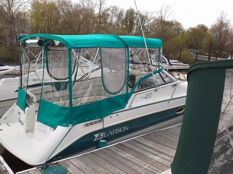 White boat with teal canopy docked at a marina with other boats in the background