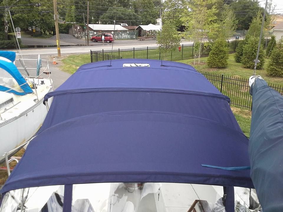 Blue boat canopy on a marina dock with trees and road in the background
