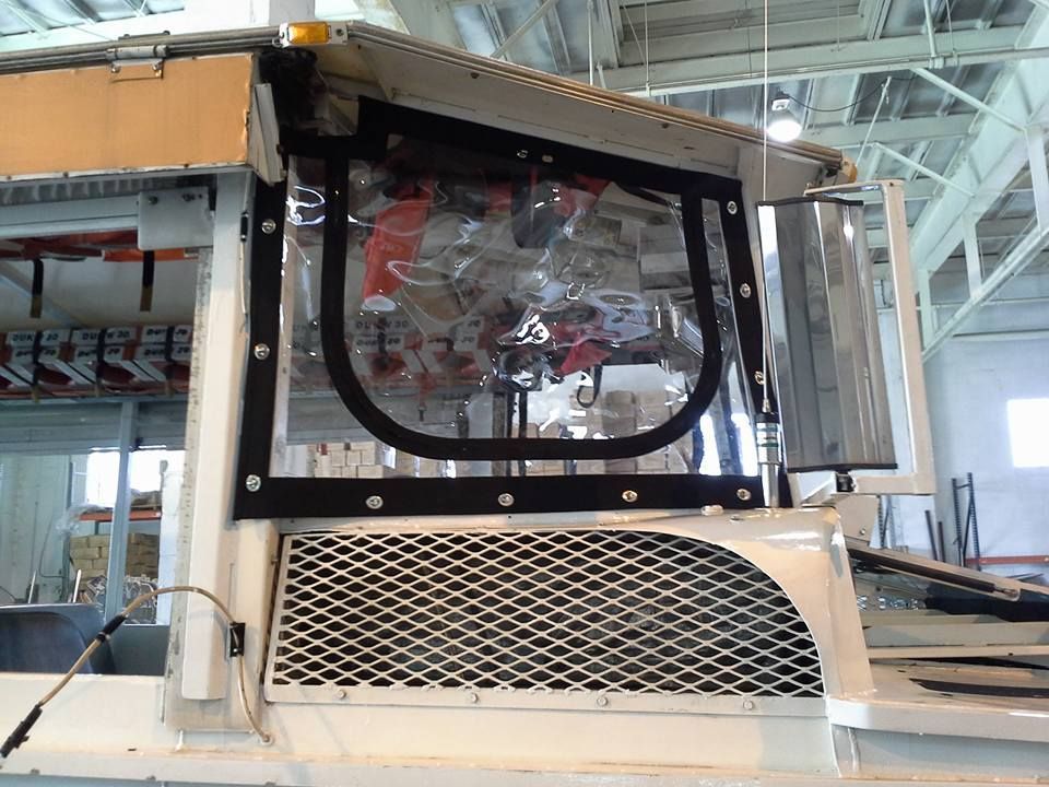 Industrial machine with clear window and metal mesh panel in a factory setting