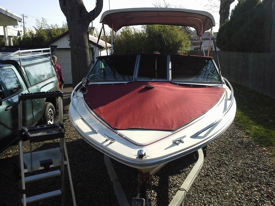 White-and-red speedboat on a trailer in a driveway, with a canopy raised over the cockpit.