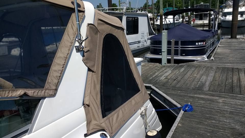 White boat with tan canopy docked beside a wooden marina pier, with another boat in the background
