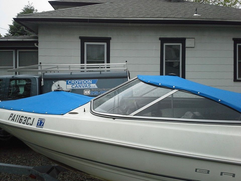 Blue-and-white speedboat beside a house, with a trailer and dock sign visible