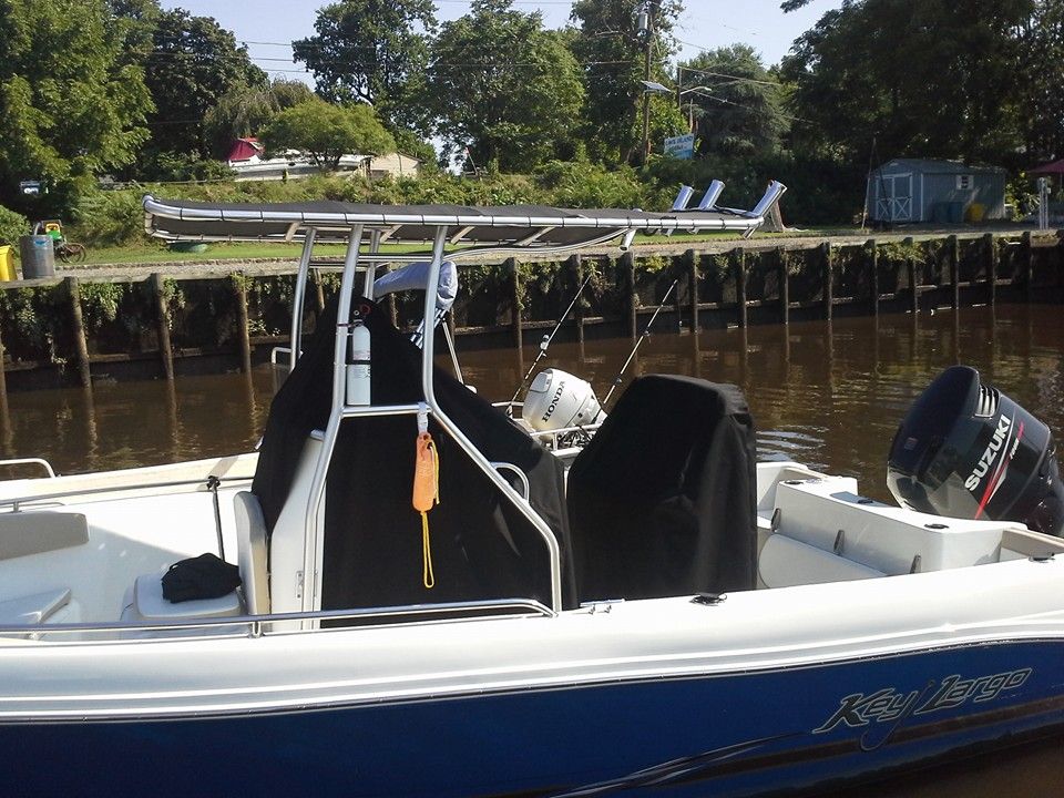 Blue fishing boat docked by a river with a canopy and outboard motor, near a wooden pier.