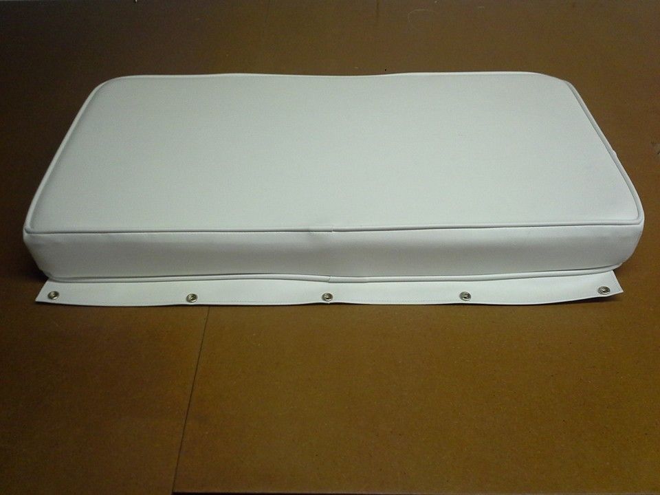 White rectangular cushion or pad on a brown surface, with a white base and visible screws