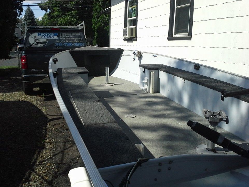 Boat trailer beside a white house, with a black truck parked behind it in a driveway.