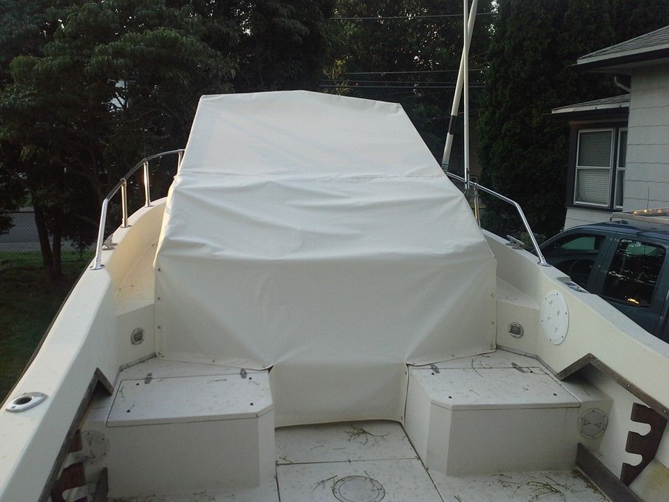 White tarp-covered boat deck with storage boxes, viewed from the stern outdoors