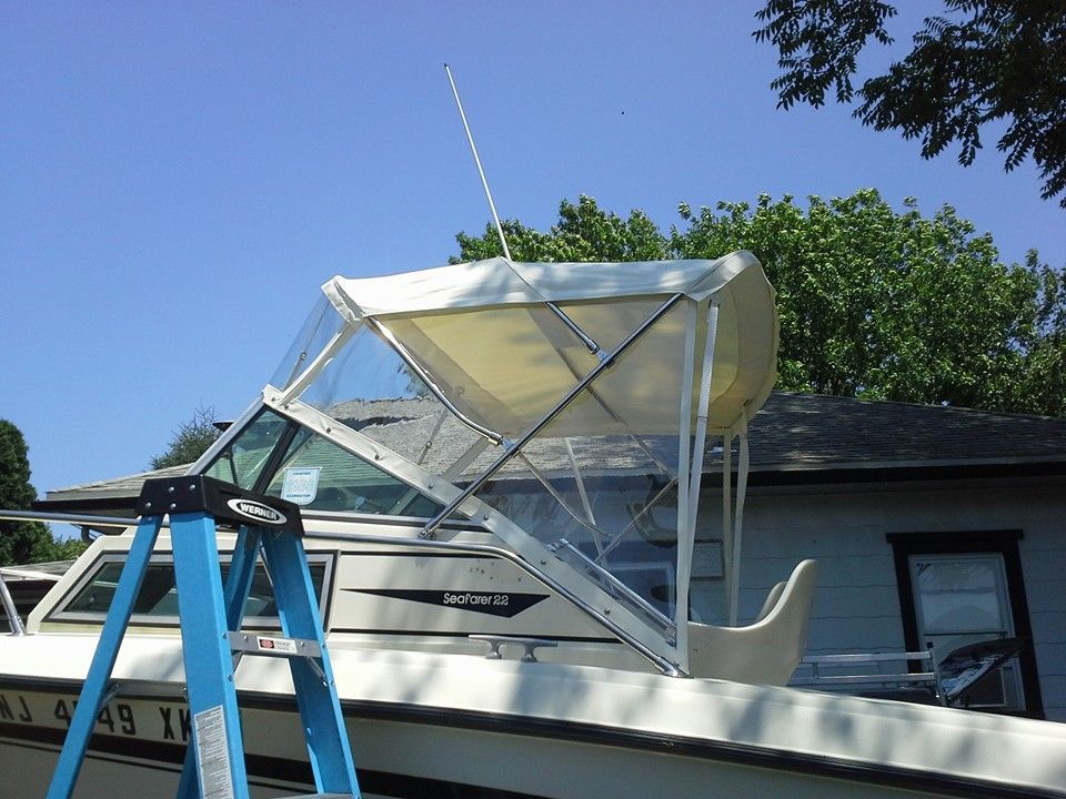 Boat on blue ladder under a white canopy beside a house and trees on a sunny day