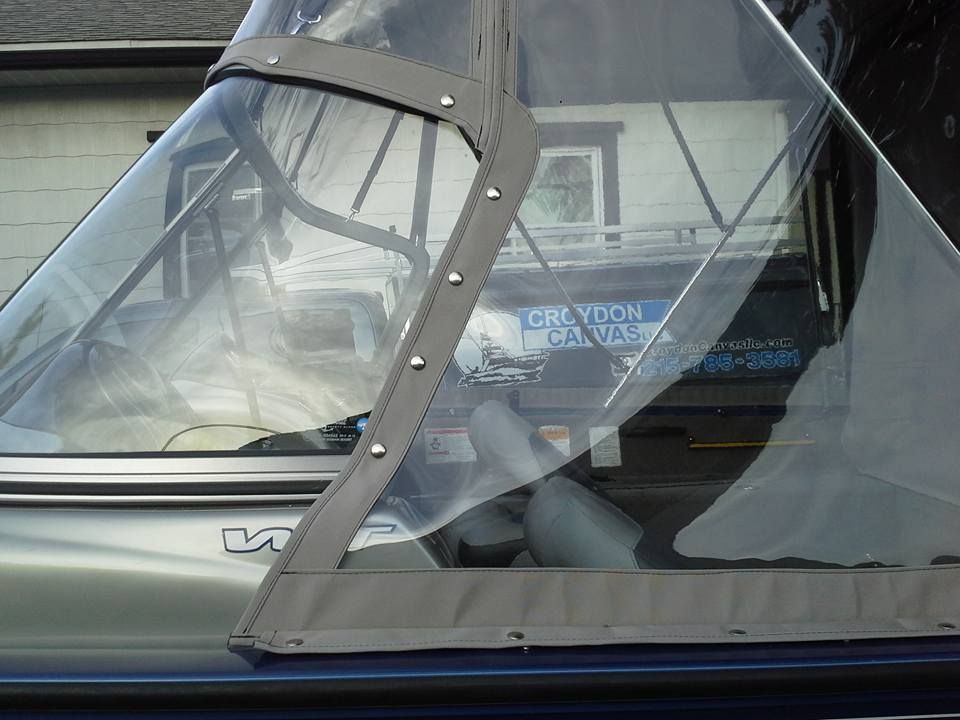 Close-up of a boat’s clear vinyl cockpit cover with gray trim and a zippered panel