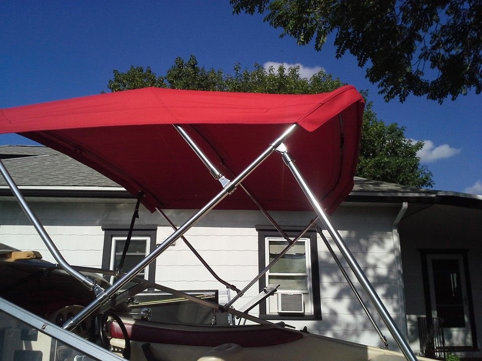 Red canopy on a metal frame over a patio beside a white house under a blue sky