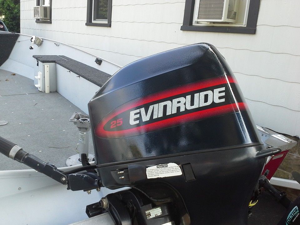 Evinrude outboard motor mounted on a boat at a dock beside a white building
