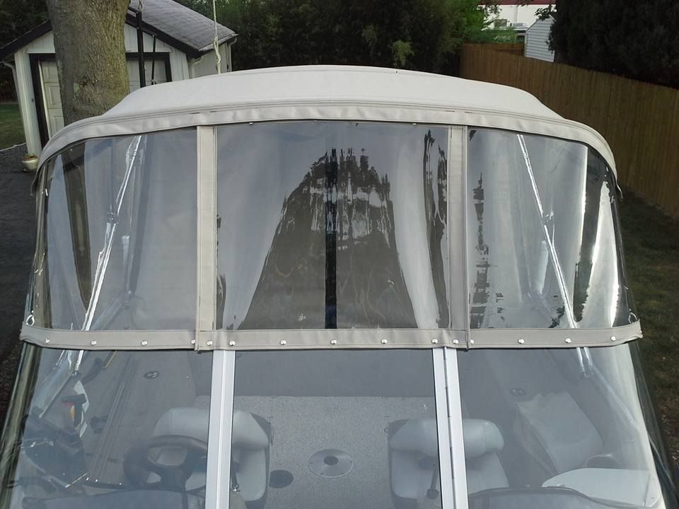 White canopy covering a boat windshield with clear vinyl curtains and gray support frame