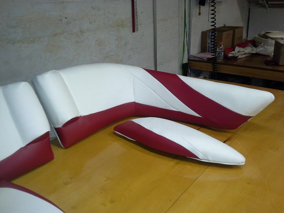White and burgundy modular sofa pieces arranged on a wooden table in a workshop