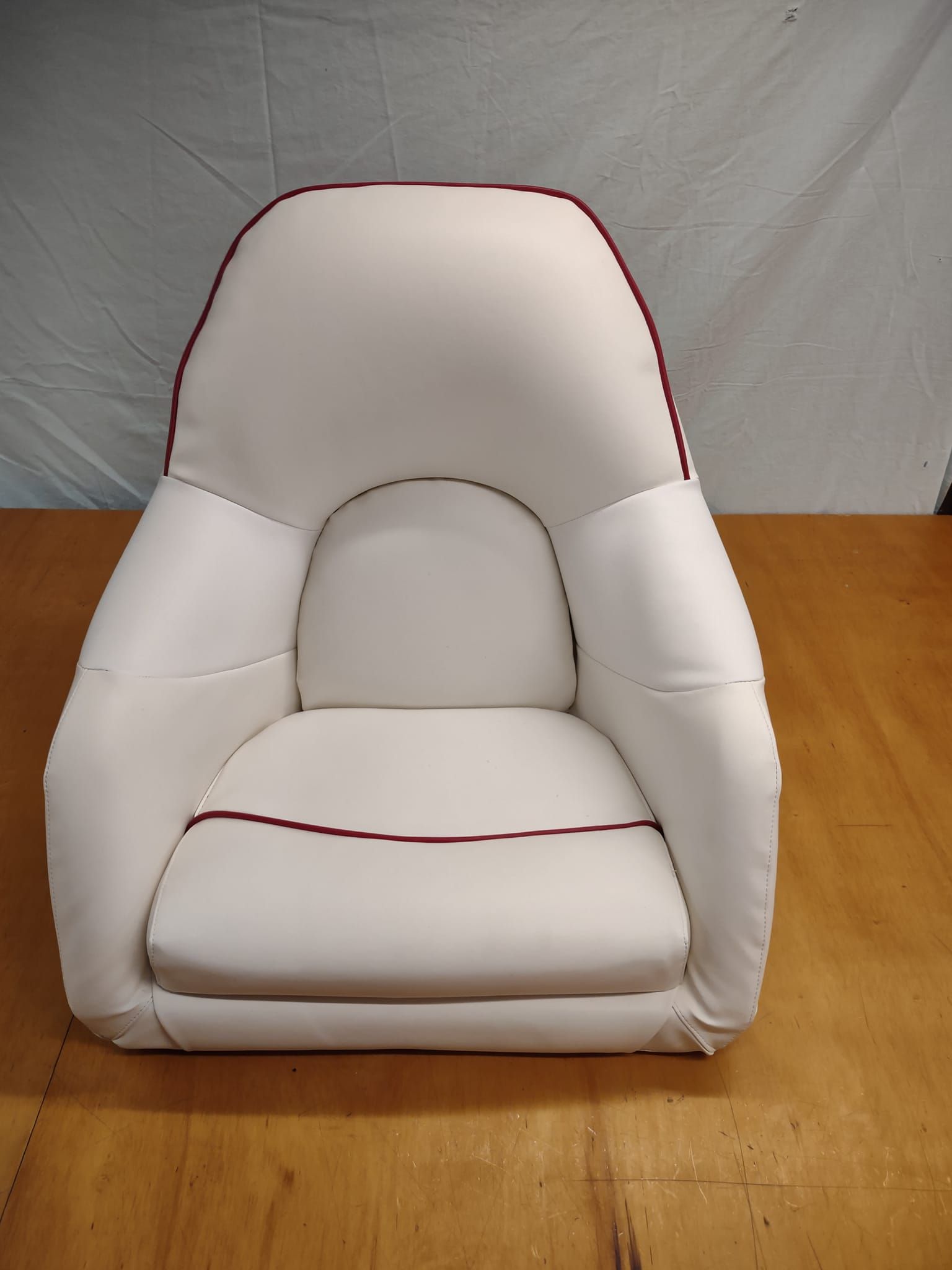 White cushioned child car seat on a wooden floor against a gray backdrop
