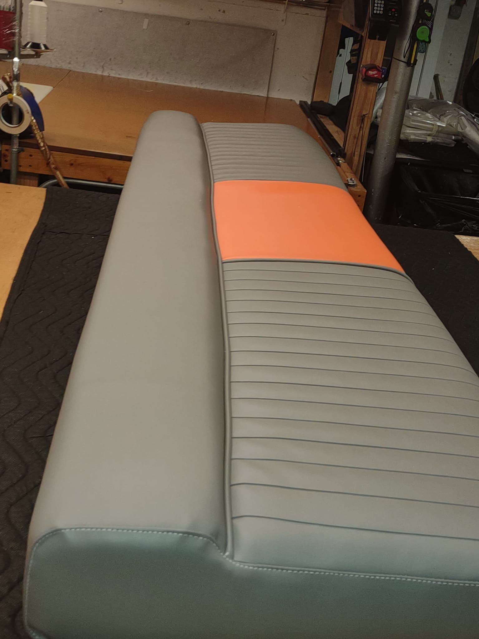 Gray and orange cushioned bench or sofa on a workshop floor