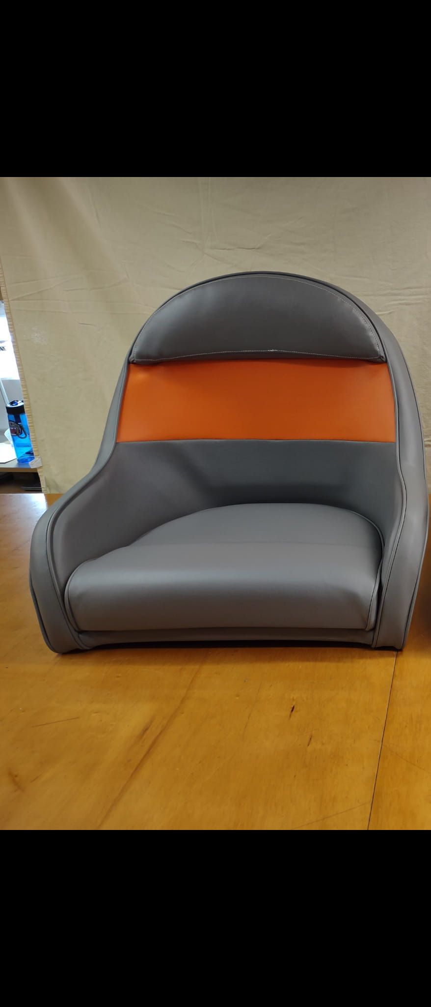 Gray-and-orange child-sized chair on a wooden floor with a curved black backrest