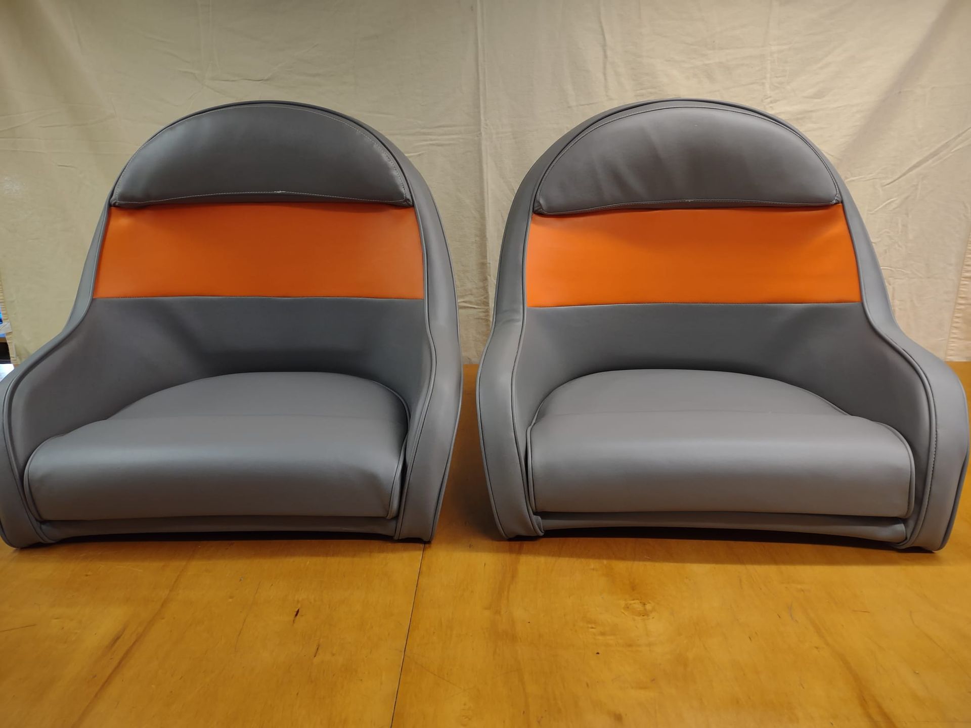 Two gray and orange floor chairs on a wooden surface with a beige backdrop