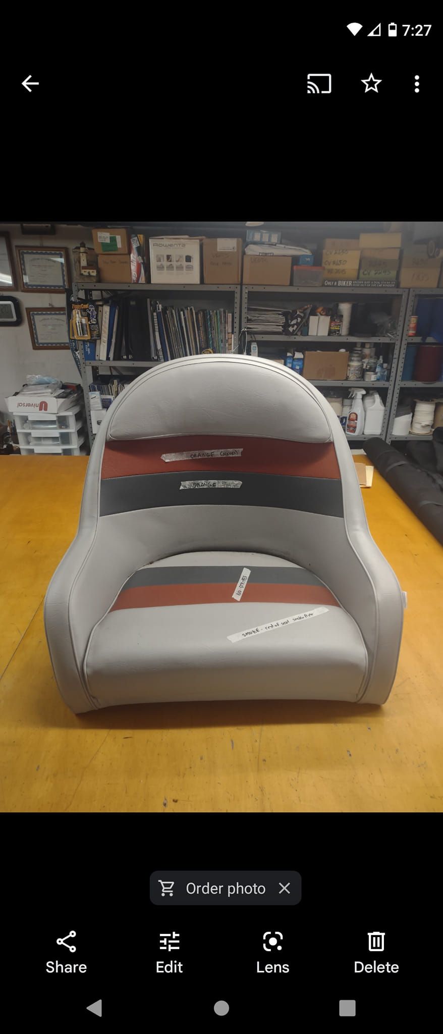 Gray cushioned chair with a red stripe, centered in a workshop or garage with shelves in the background