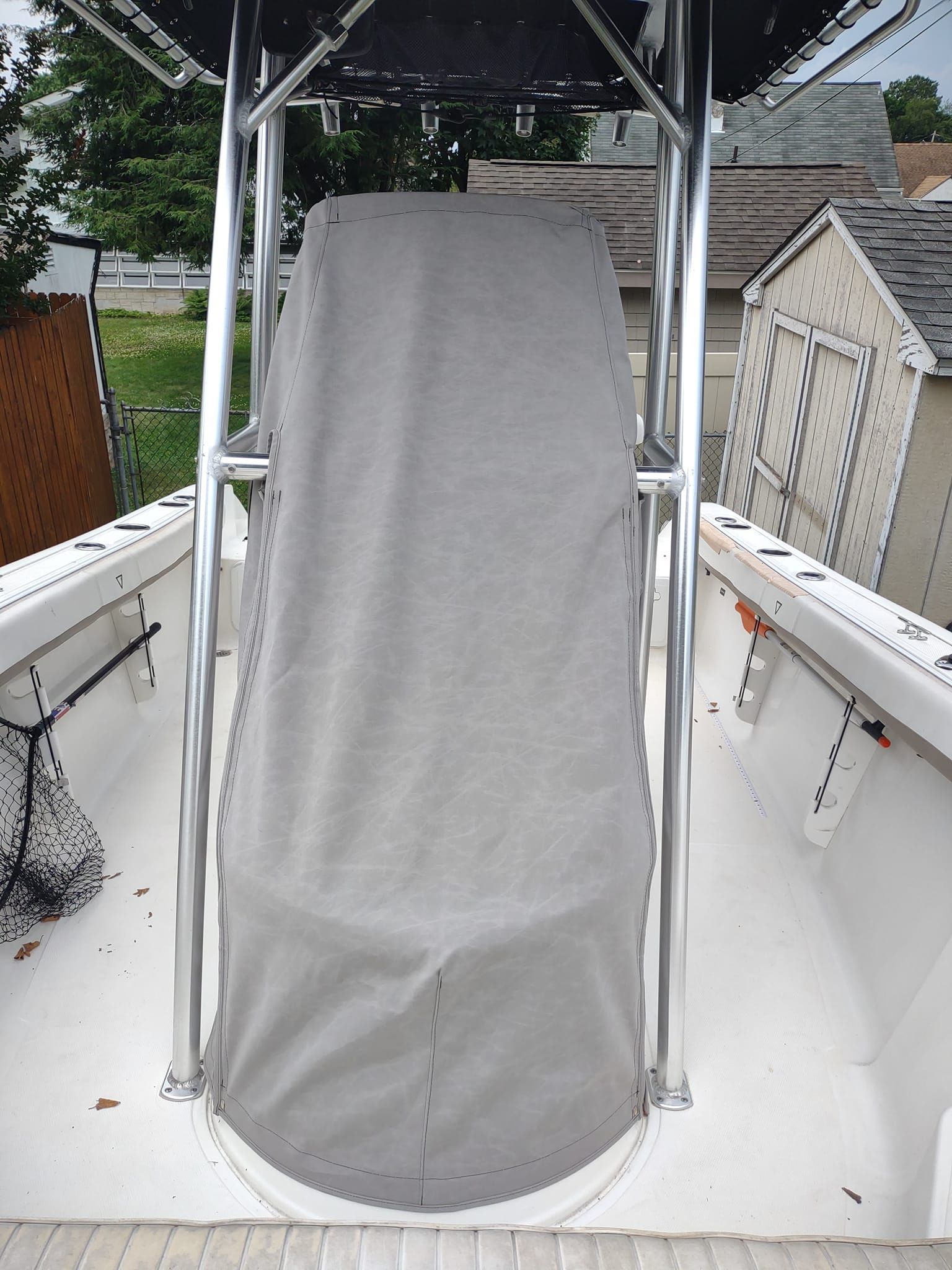Gray-covered chair on a boat deck under a canopy, with white railings and calm water nearby