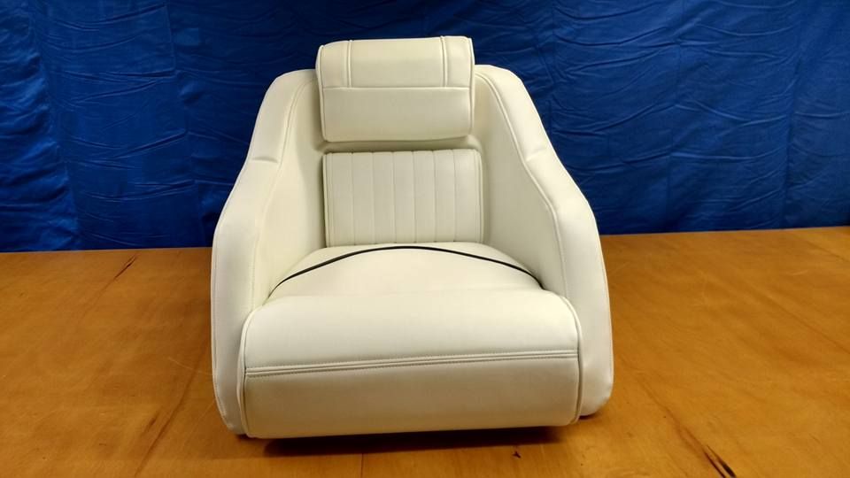 White upholstered chair with padded armrests on a wooden floor against a blue backdrop