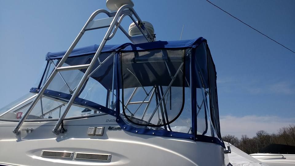 White boat with blue canvas canopy and metal frame against a clear sky