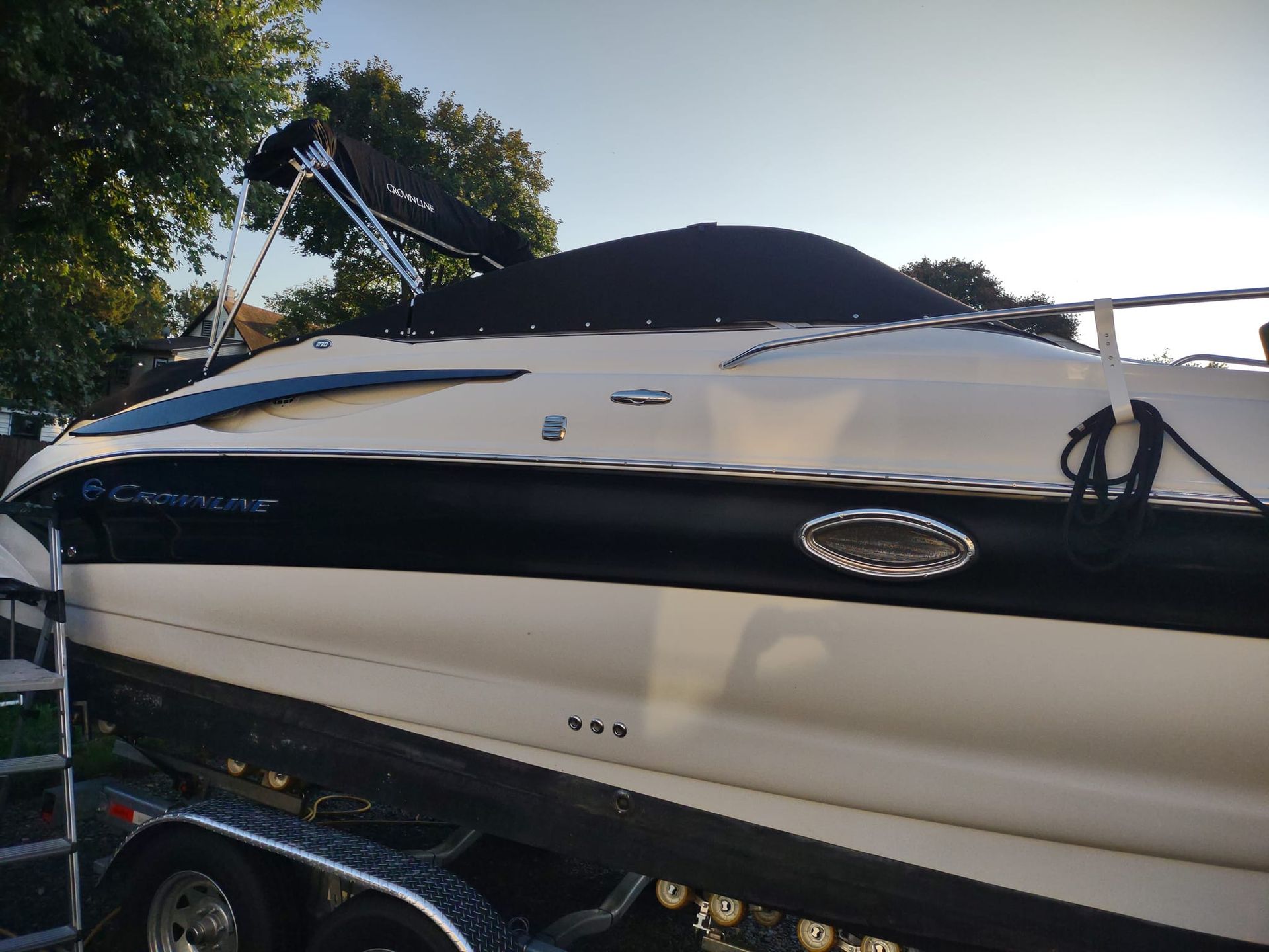 Black-and-white motorboat on a trailer outdoors, with trees and sky in the background.