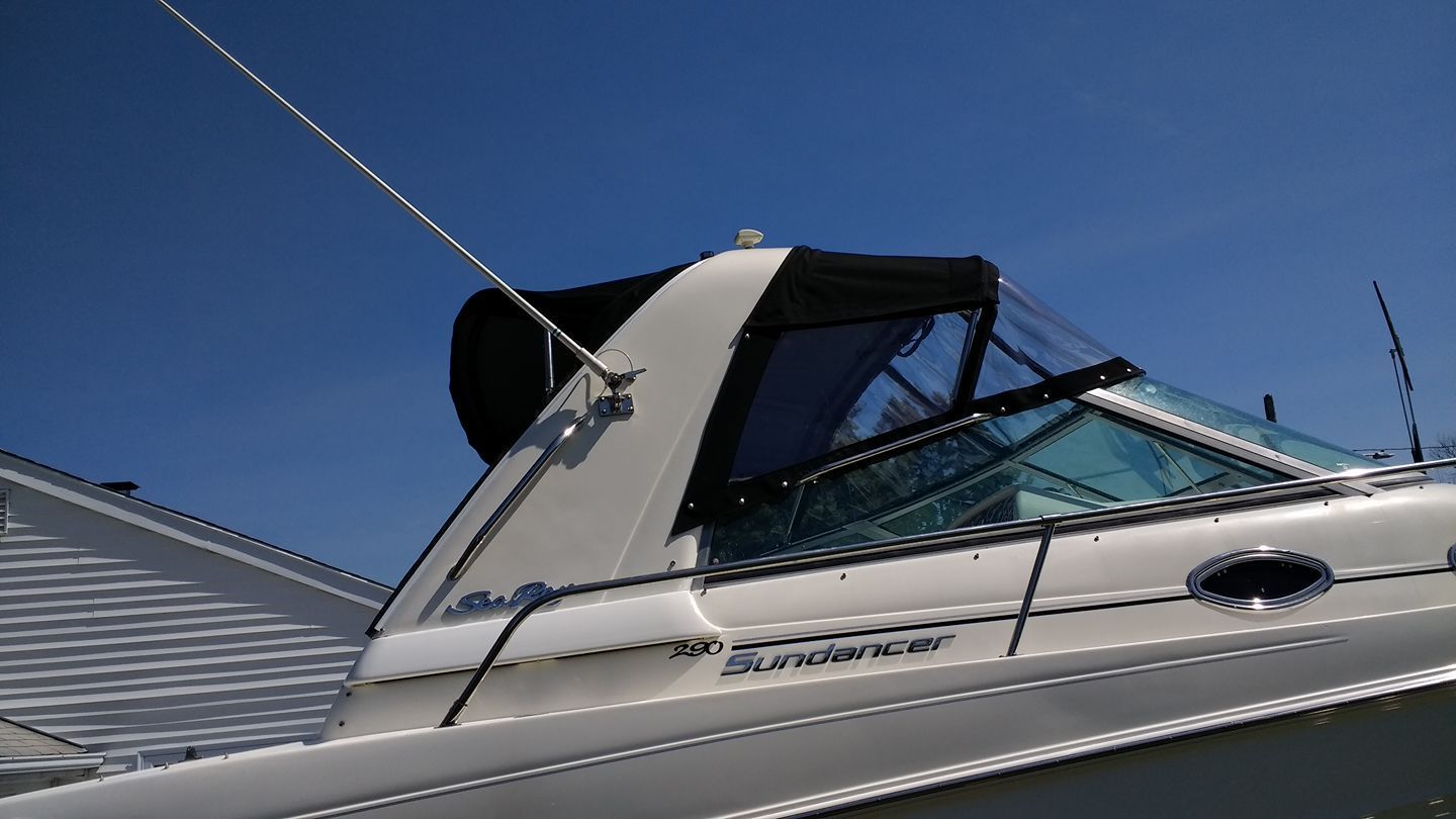 White motorboat with blue-tinted windshield and dark canopy moored under a clear blue sky.