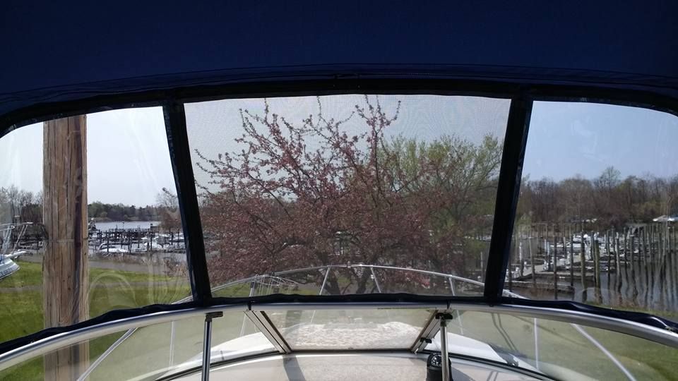 View through a boat windshield toward a tree-lined shoreline on a gray day
