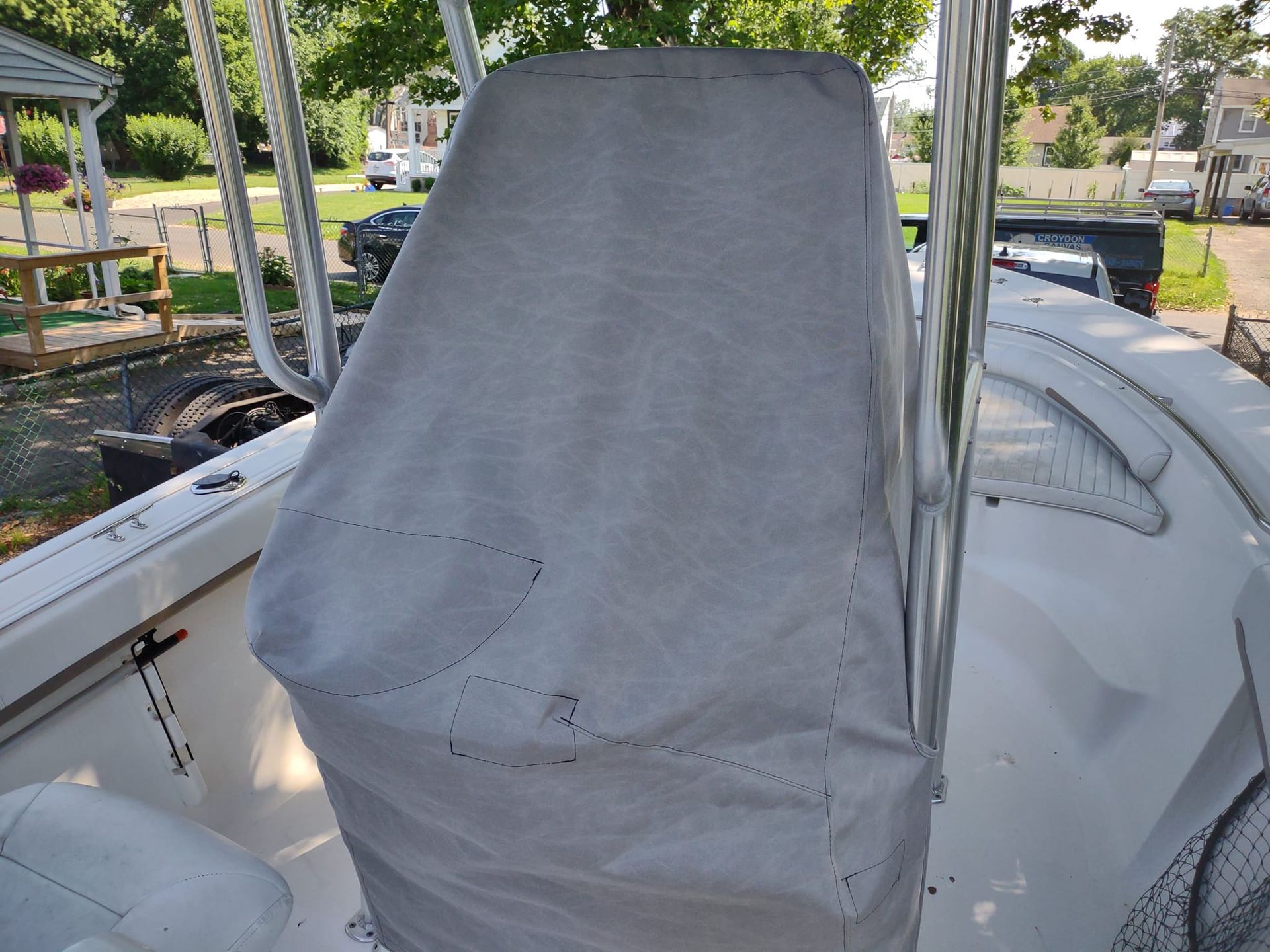 Covered boat seat on a docked boat, with marina water and trees in the background