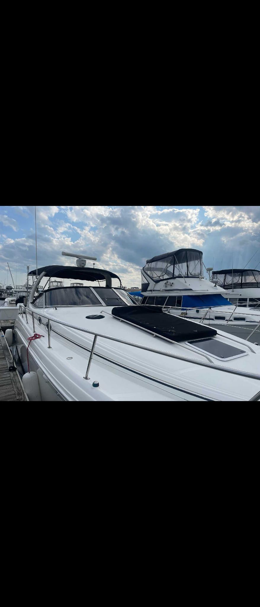 White yachts docked at a marina under a cloudy blue sky