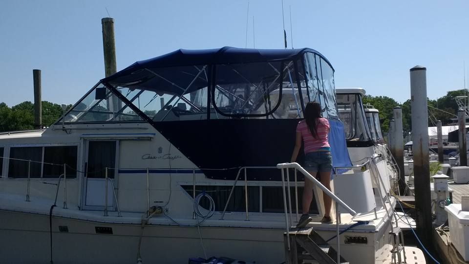 Person boarding a white boat at a dock, under a dark blue canopy.