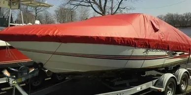 Red-covered boat on a trailer parked outdoors in a lot