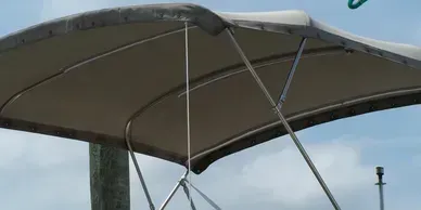 Metal frame and taut gray canopy of a shelter against a cloudy sky
