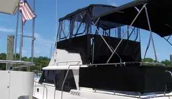 White boat with a black canopy docked beside an American flag on a sunny day