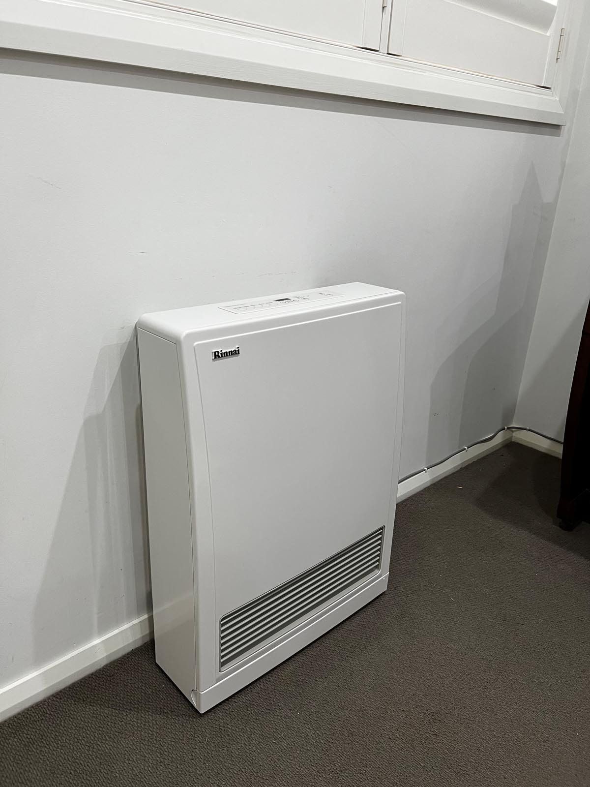A white heater is sitting on the floor next to a window in a room.